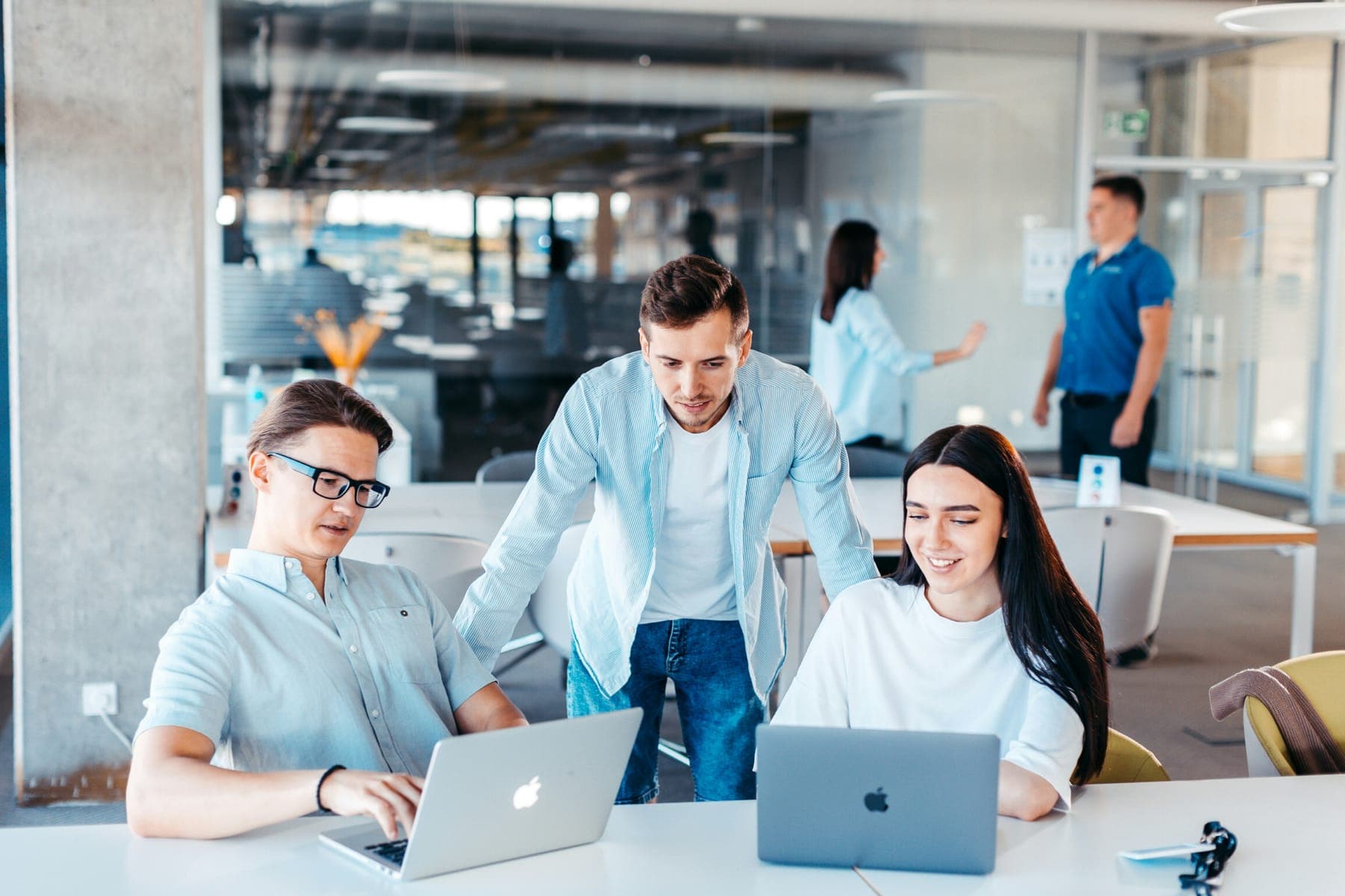 Three colleagues working on laptops in a bright, open-plan office