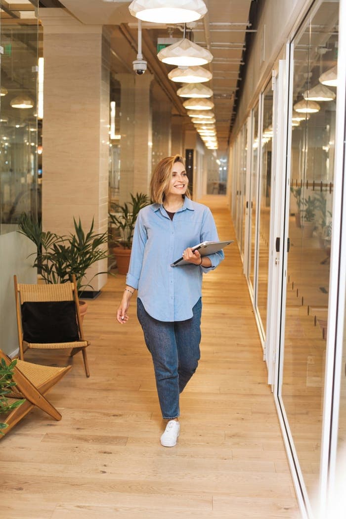 A consultant walking through a bright office corridor with a tablet